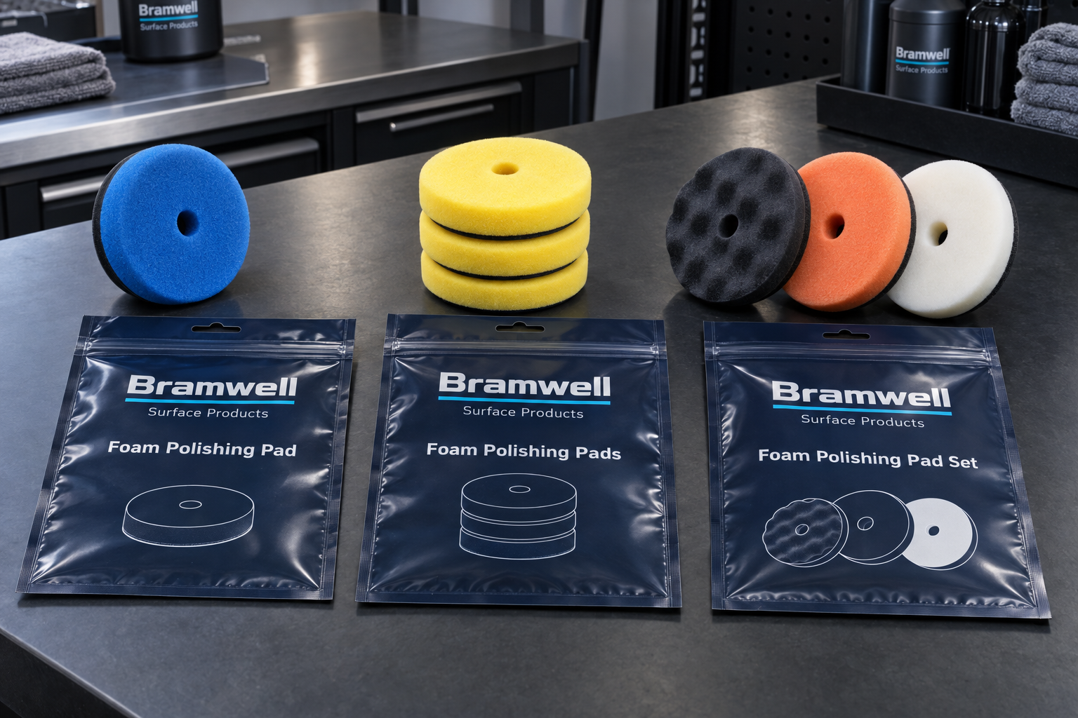 Single foam polishing pad, same-stage stack and three-pad set arranged beside coordinated fictional pouch artwork on a detailing workbench.